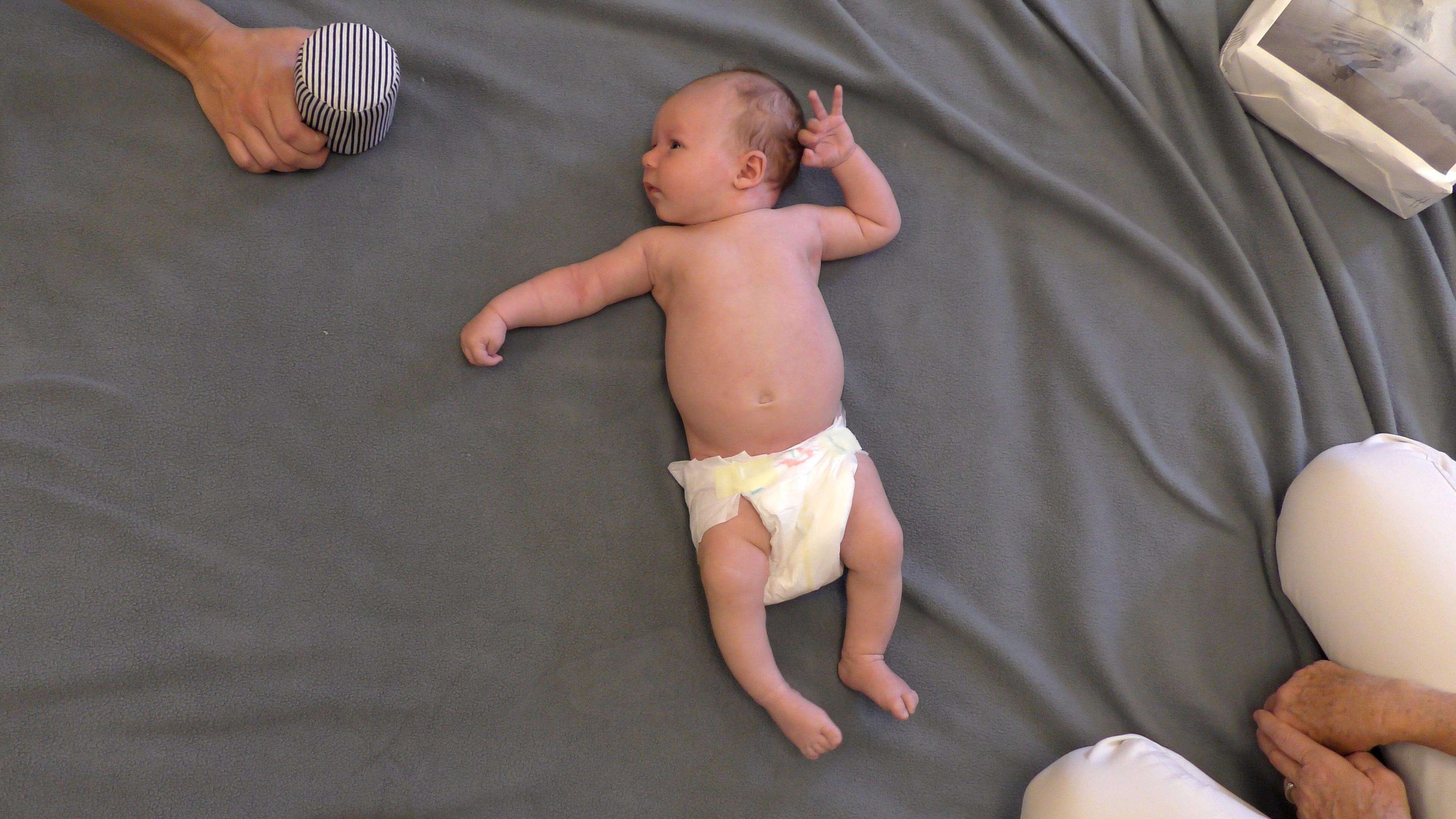 Baby lying on floor wearing diaper that is too low and too loose.