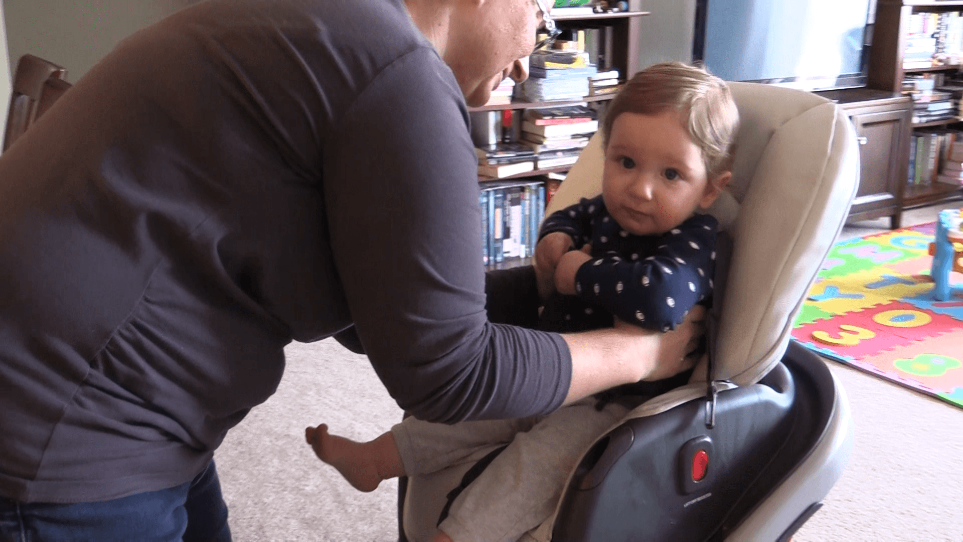 Mother bending down to lift baby boy out of his high chair.