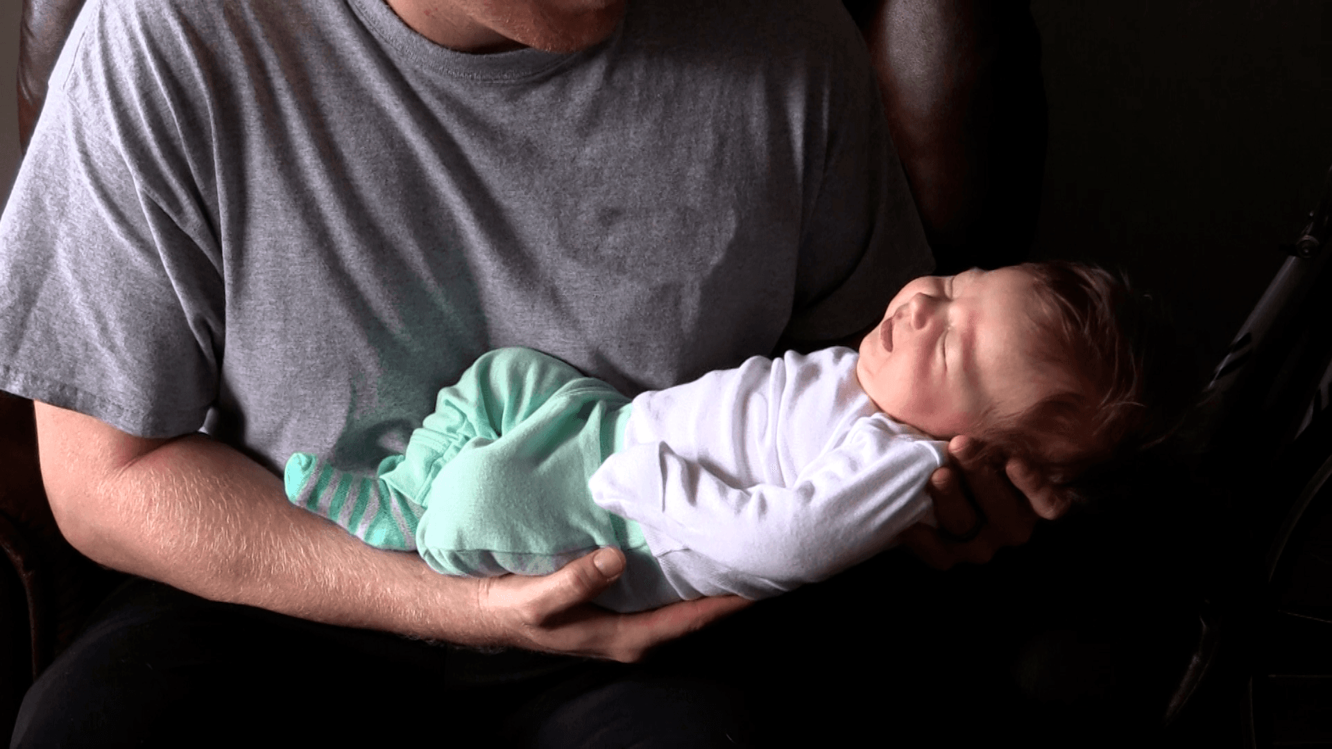 Father calming Baby by rocking him in his arms.