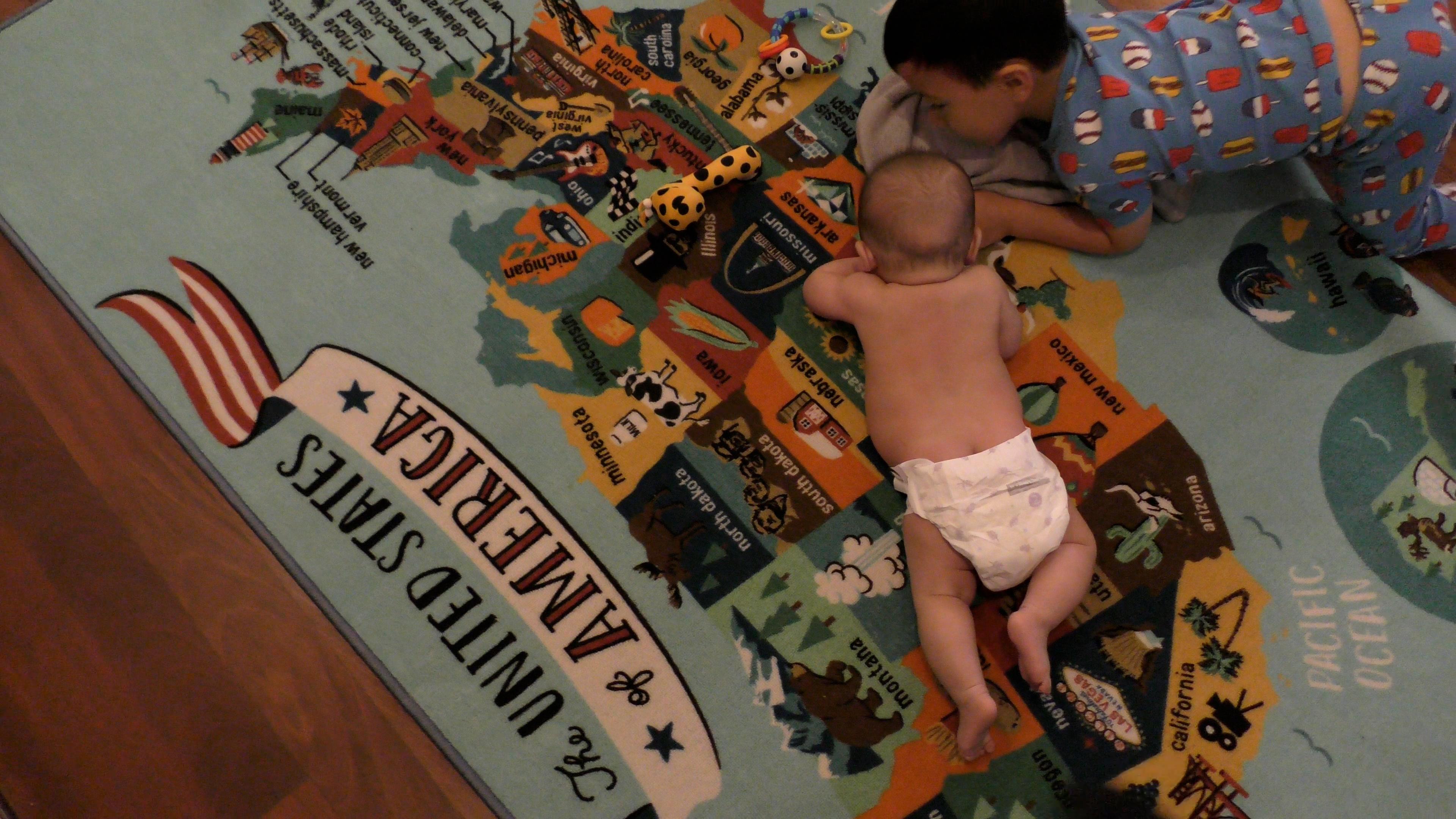Toddler boy playing with baby brother during Tummy Time.