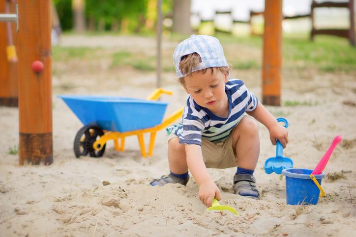 Young boy engaged in sand play outdoors, exploring textures and building fine motor skills.