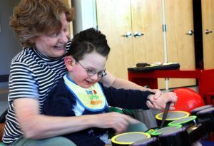 boy with glasses playing drums with occupational therapist