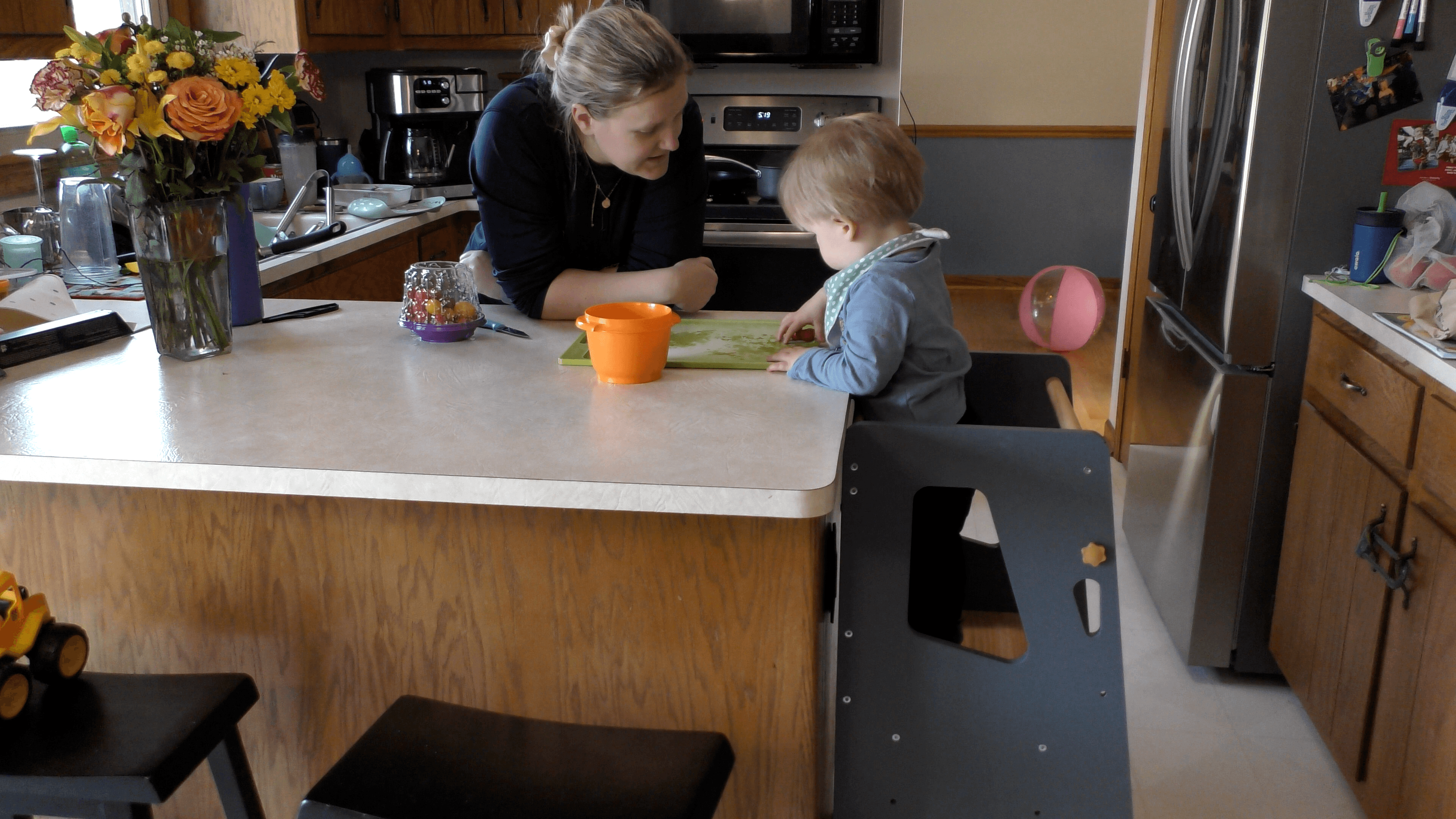 Mother and toddler preparing a snack at the kitchen counter.