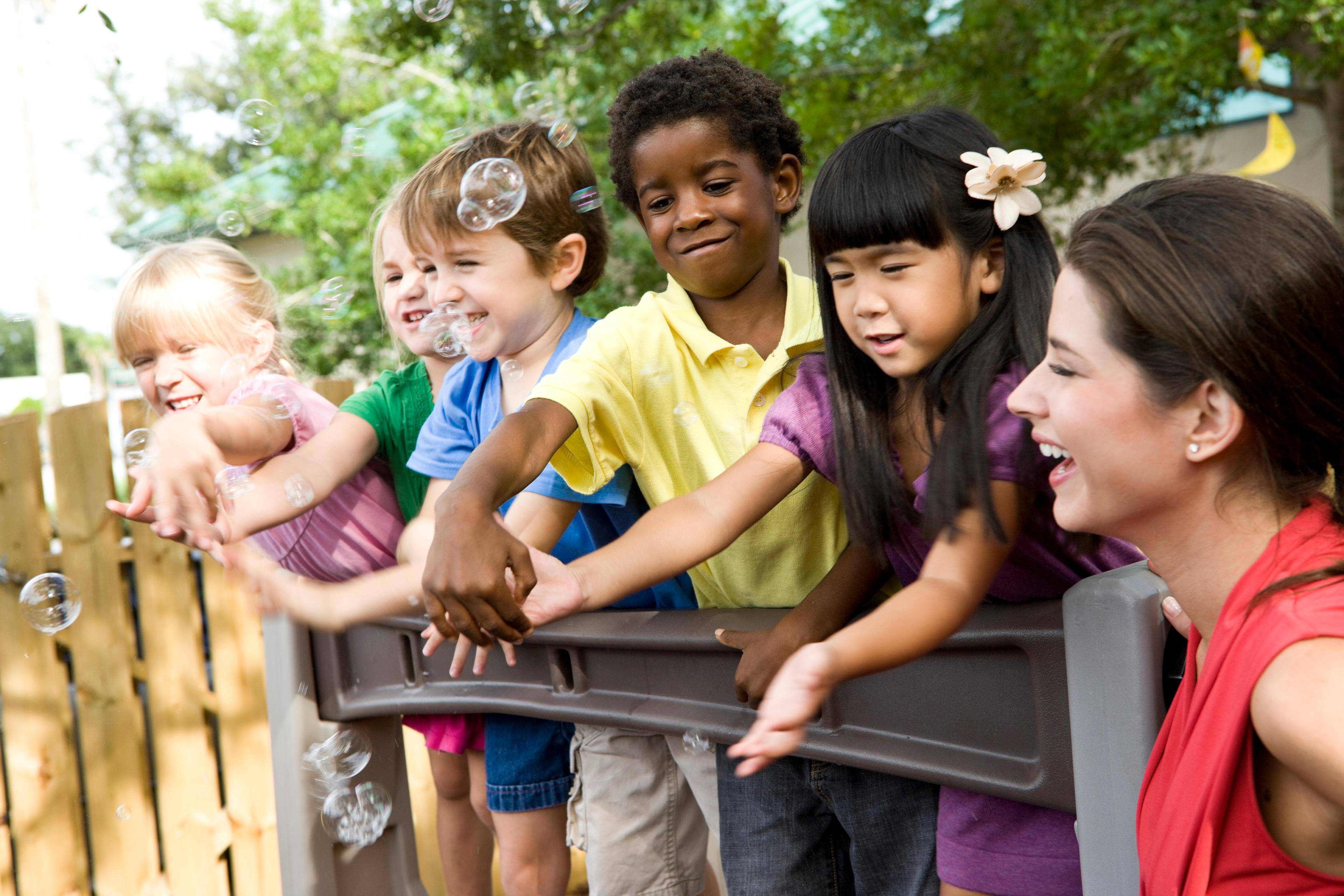Children playing with bubbles outside to improve gross motor skills and visual tracking.