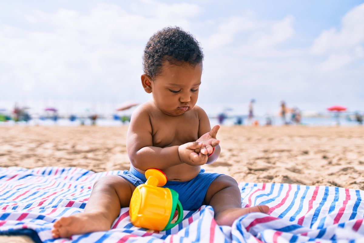 toddler-playing-with-toys-sitting-on-the-sand-at-the-beach